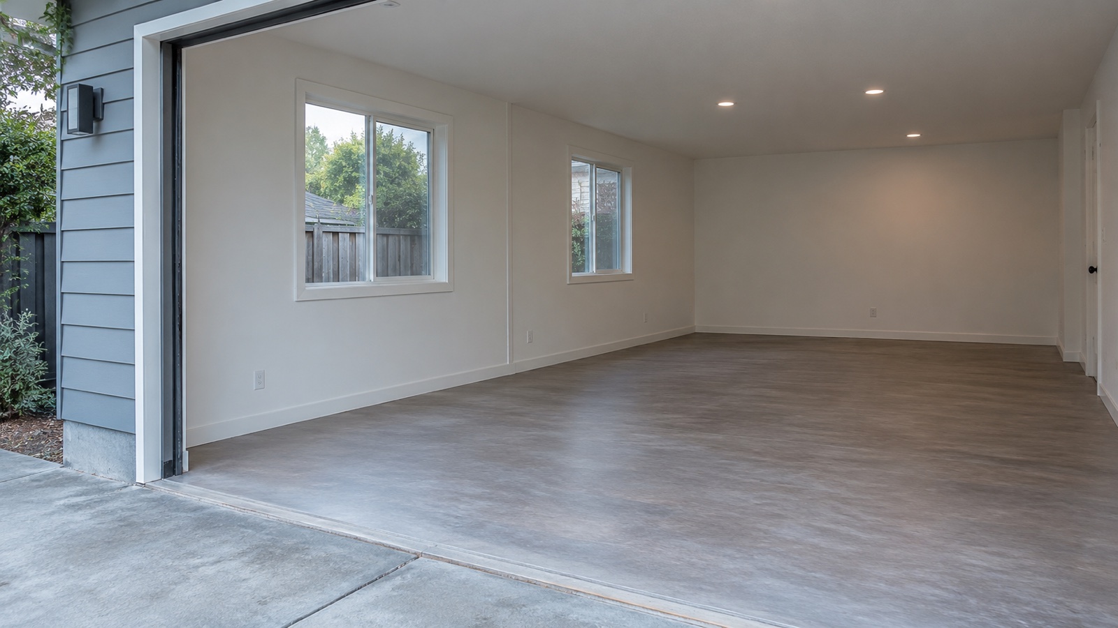 Fictional converted garage interior viewed from the driveway while a seller checks past alterations